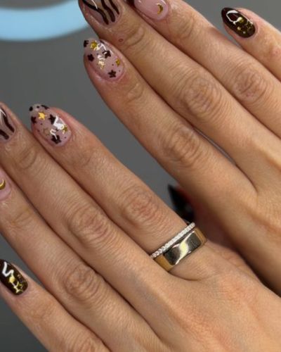 Uñas café con estrellas y lunas doradas